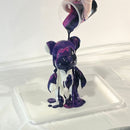 mixture of coloured paints being poured on a bearbrick canvas