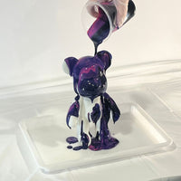 mixture of coloured paints being poured on a bearbrick canvas